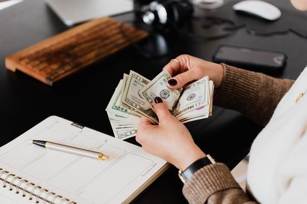 Une femme compte des billets de 20 dollars.