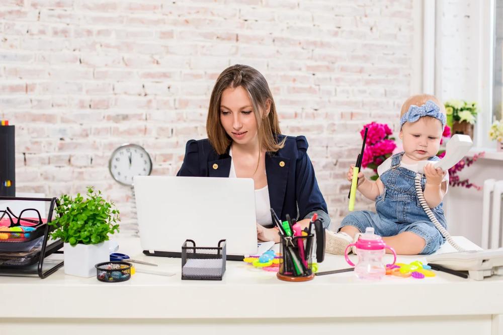 Une mère travaille sur son ordinateur portable avec sa fille à côté delle.